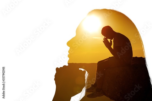 Young man pray outdoor on top of mountains in the sunset