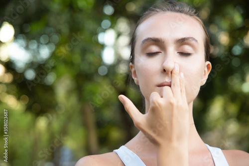 woman practicing yoga breathing technique, surya bheda pranayama, the sun breathing with one nostril