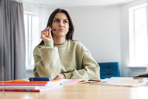 Photo of concentrated student woman thinking while doing homework