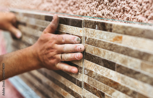 Master tiler glues wall tiles. Concept of the contruction.