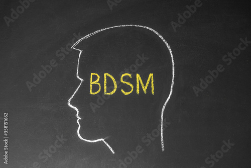 Concept man thinks about BDSM. Male head and the inscription BDSM on the chalk board.