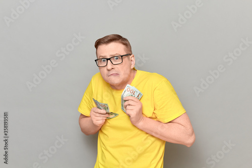 Portrait of funny greedy man holding money in hands and counting cash