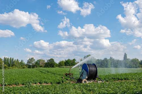 Irrigation hose reel, Agricultural Travelling Irrigator or Hose Reel Irrigation Sprinkler Machine with Water Sprinkler set up on agricultural field on countryside in Germany.