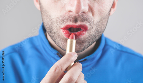 Man applying red lipstick on lips.