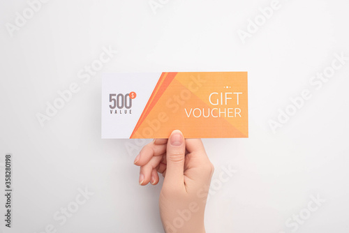 Top view of woman holding gift voucher with 500 value lettering on white background