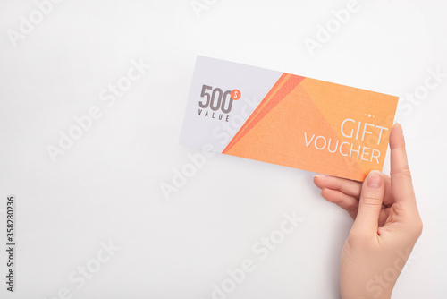 Cropped view of woman holding gift voucher with 500 value lettering on white background