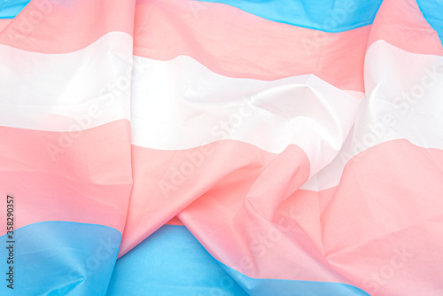 Transgender fabric flag with white, pink, blue strips. Close-up transgender pride flag as background or texture
