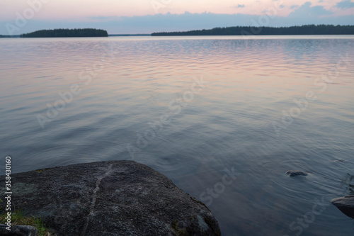 Russia, Karelia. White nights. Dawn on Lake Muezero. Big stone lies near the water