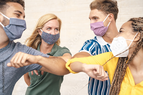 Young friends wearing face mask doing new social distancing greet with elbows bumps for preventing corona virus spread - Physical distance and friendship safety greetings concept