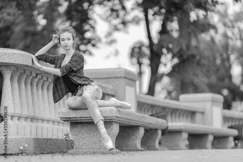 Black and white photo of a ballerina girl in jeans and pointe shoes, dancing and posing in the city on the street