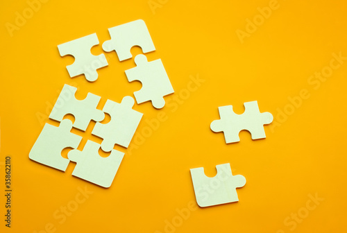 Model of a house on a uniform orange background for the concept of real estate loans with space for text. Close-up puzzles for purchasing housing and buying on credit, and two puzzles side by side
