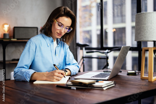 Young woman working with a laptop. Female freelancer connecting to internet via computer. Blogger or journalist writing new article.