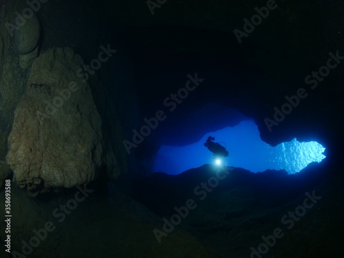 cave diving underwater scuba divers exploring caves ocean scenery sun beams and rays background