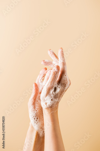 cropped view of female hands in soap foam isolated on beige