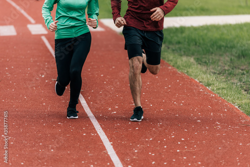 Cropped view of couple jogging together on running track in park