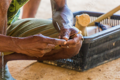 TAMAN NEGARA, MALAYSIA - MARCH 17, 2018: Indigenous man making darts for a blowpipe in his village in Taman Negara national park, Malaysia