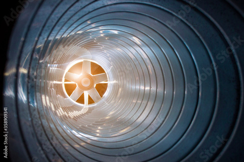 closeup view from inside the galvanized steel air duct on the exhaust fan in the background light, the front and back background is blurred with a bokeh effect