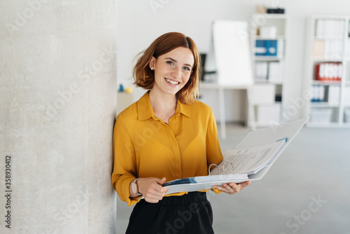 Attractive young office worker holding large file