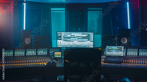 Shot of a Modern Music Record Studio Control Desk with Computer Screen show User Interface of DAW Software with Song Playing. Equalizer, Mixer and other Professional Equipment.
