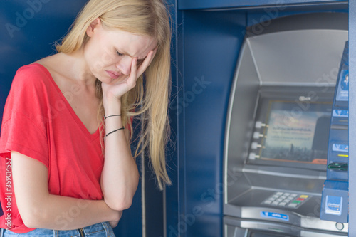 Sad woman next to ATM bank machine in debt and no money.