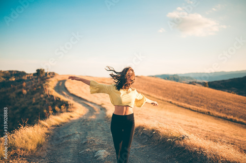 Ragazza felice si diverte in una strada di campagna con maglia gialla e pantaloni neri.