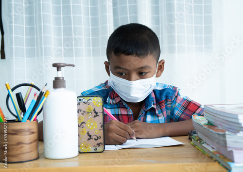 Cute little asian boy Learning online with smartphone at home ,coronavirus