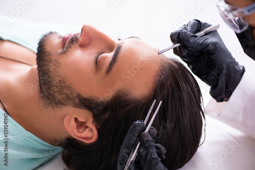 Young man visiting female beautician in hair transplantation con