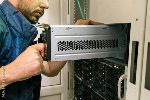 Maintenance of data center equipment. The technician installs a new battery pack into the uninterruptible power supply. Replacing the power module in the server room rack.