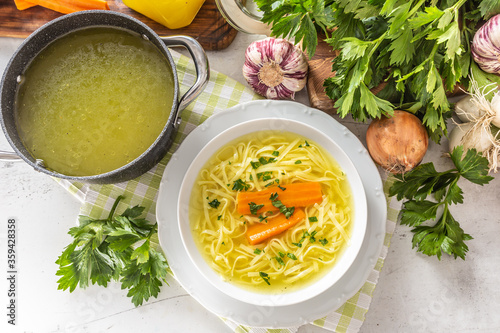 Chicken soup broth in a plate carrot onion celery herbs garlic and fresh vegetables