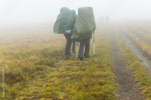 A group of hikers walk in the fog.