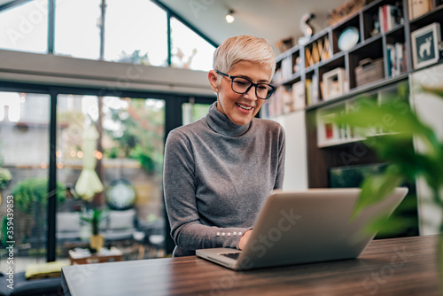 Portrait of a cheerful mature businesswoman working on laptop at home office.