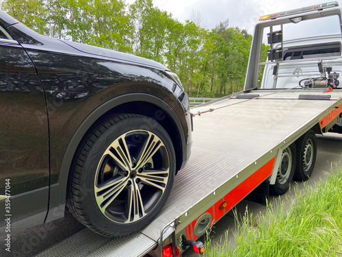 Black new SUV is pulled onto a tow truck