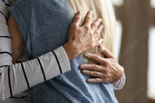 Close up image elderly woman hugs younger relative girl. Grown up adult daughter or granddaughter enjoy moment cuddle to old mom or aged granny. Family bond, together in trouble and happiness concept