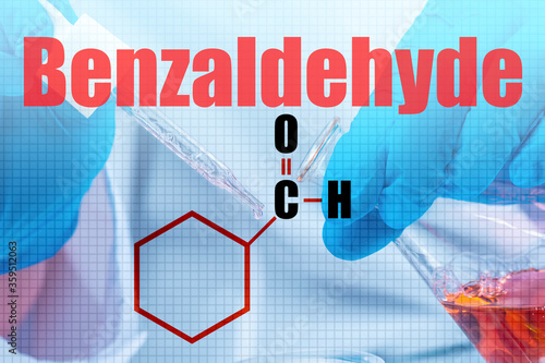 The big word is Benzaldehyde and the molecular formula. The concept of benzoin aldehyde against the background of a chemist's hands with a flask and pipette. Phenylmethanol. Toxic substance.