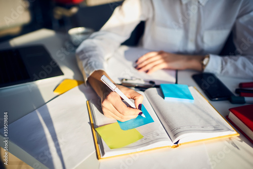 Cropped image of creative female secretary creating planning for executive noting important meeting and events organizing work of busy boss while sitting at working place in coworking office