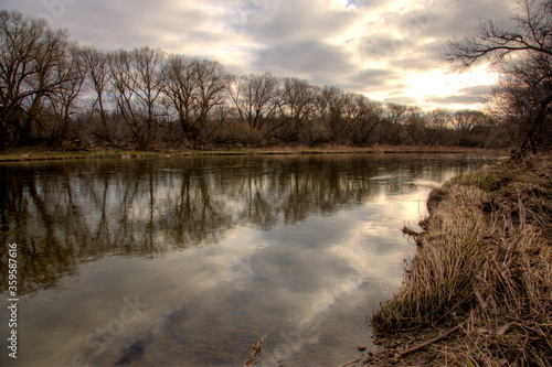 The Grand River lined by leafless willow trees, shot at sunrise in early spring. Shot in Kitchener, Ontario, Canada.