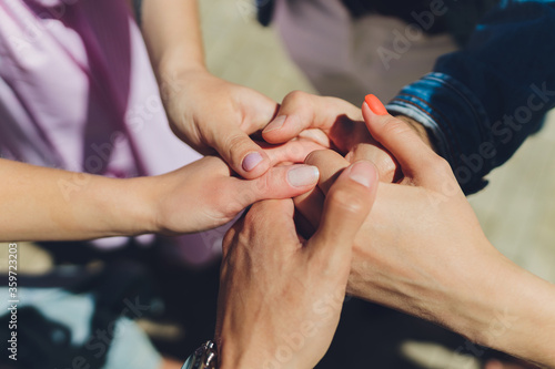 two man and three women holding hands on a table implying a polyamory relationship or love triangle.