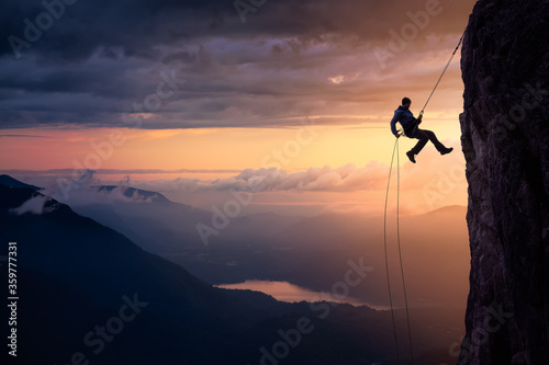 Epic Adventurous Extreme Sport Composite of Rock Climbing Man Rappelling from a Cliff. Mountain Landscape Background from British Columbia, Canada. Concept: Explore, Hike, Adventure, Lifestyle