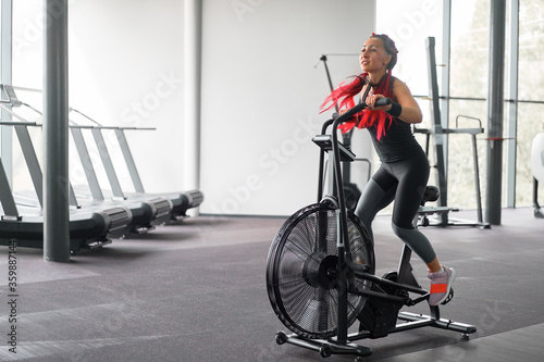 Woman exercise bike gym cycling training fitness. Fitness male using air bike cardio workout.