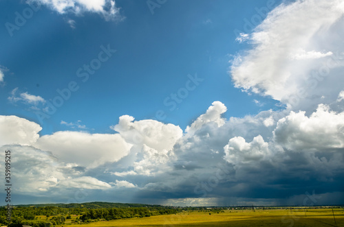 A large white cumulus cloud, oddly shaped against the blue sky, hovered over a green field.