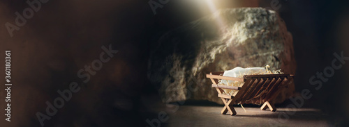 Christian Christmas concept. Birth of Jesus Christ. Wooden manger in cave background. Banner, copy space. Nativity scene symbol. Jesus is reason for season. Salvation, Messiah, Emmanuel, God with us