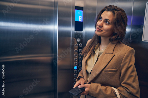 Successful business lady going down in elevator