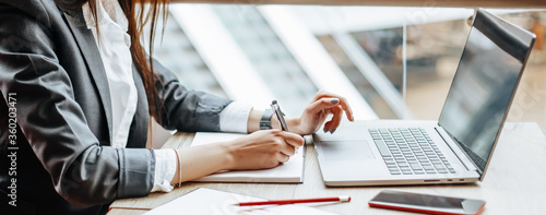 Girl works on a laptop in the workplace. Successful business woman creates a startup and makes decisions.