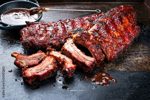 Barbecue pork spare loin ribs St Louis cut with hot honey chili marinade burnt as closeup on an old rustic board