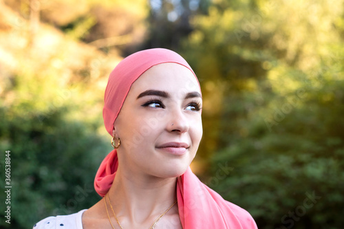 Woman with cancer wearing a pink scarf looking optimistic