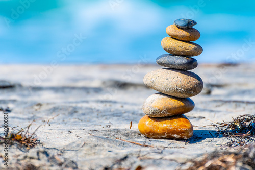 Stacked stones/ pebbles naturally balanced on beach sand on a sunny summer day. Rock Zen stack balancing. Meditation symbol of peace and harmony.