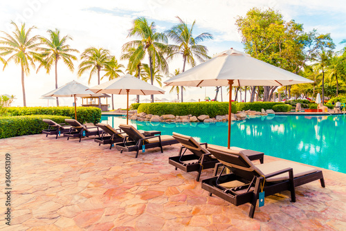 Umbrella and chair around swimming pool in resort hotel for leisure travel and vacation neary sea ocean beach