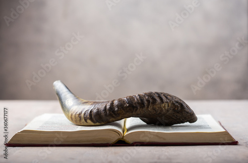 Rosh Hashanah (Hashana) (jewish New Year holiday) concept with Ram shofar (horn) with religious holy prayer book on table