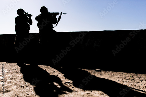 Silhouette of two us army soldiers patrolling the streets standing in a building