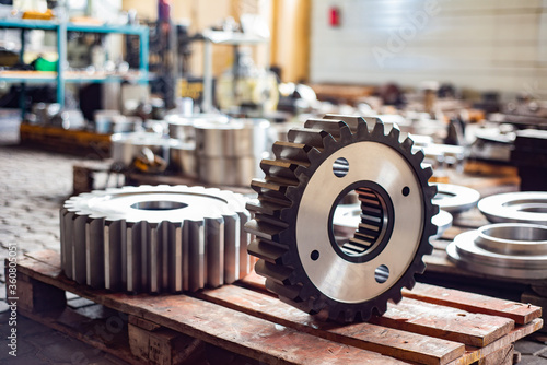 Two large gears after heat treatment lie on a wooden rack. Gear cutting and milling in heavy industry.